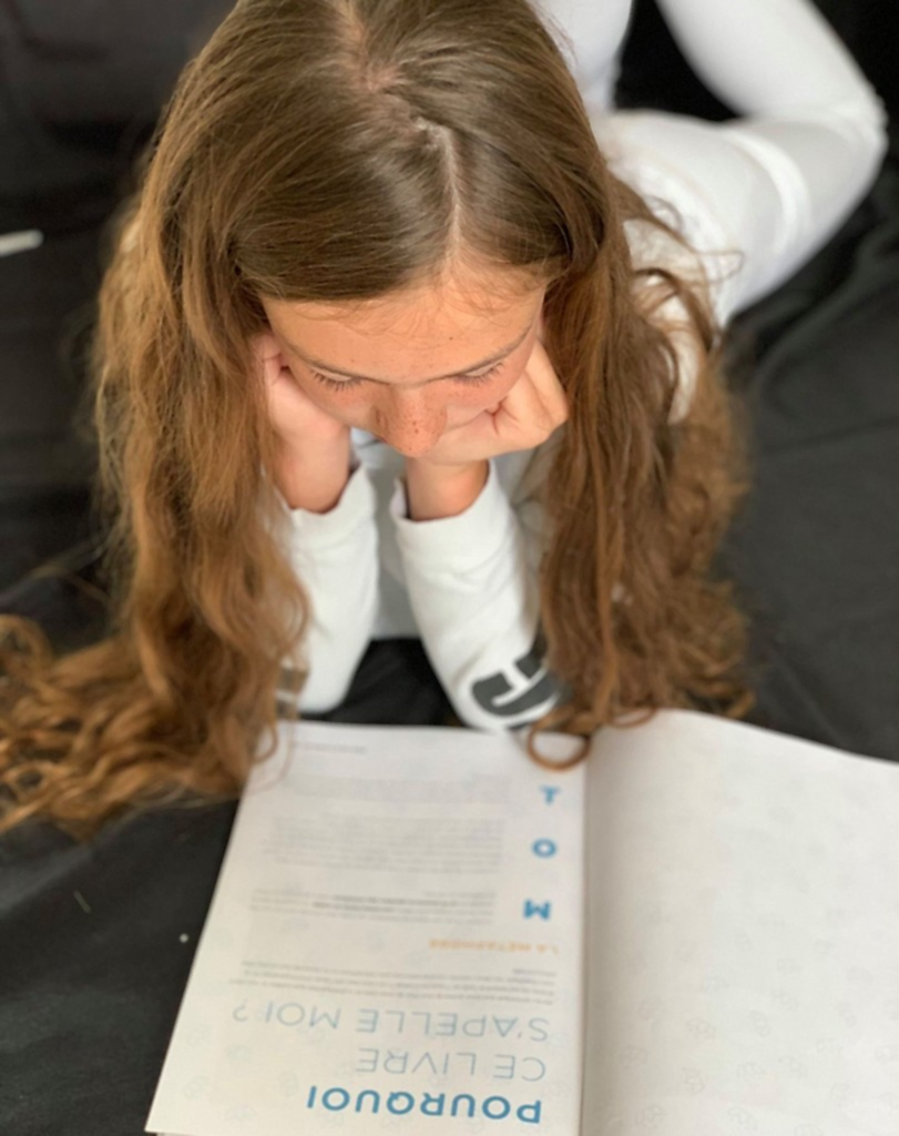 Un enfant absorbé par la lecture d'un tome de la collection MOI